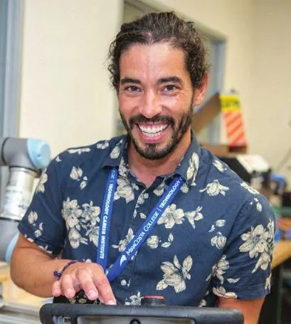 Marcelo Goncalves, a MiraCosta Technology Career Institute alum, smiling in a robotics lab